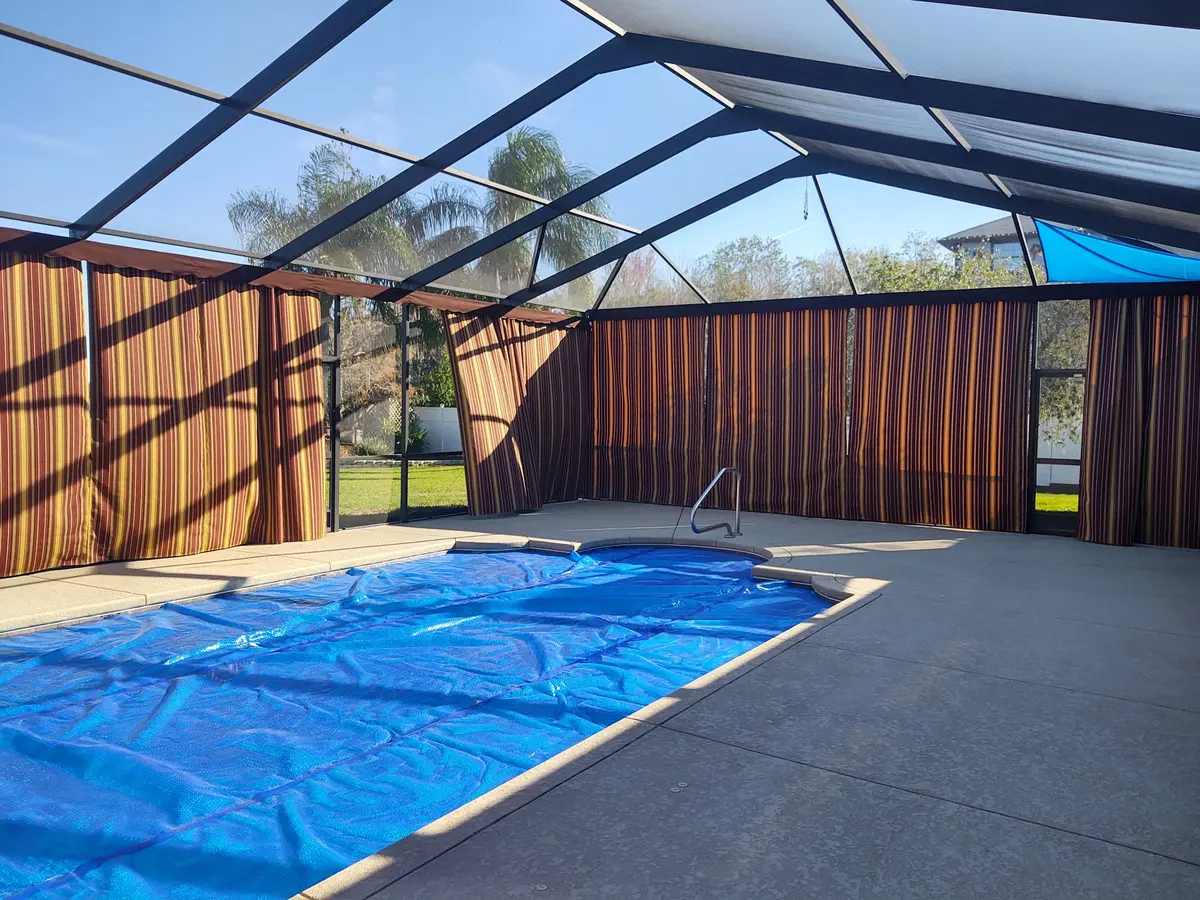 Striped privacy curtains with shade sail in Southwest Florida pool enclosure