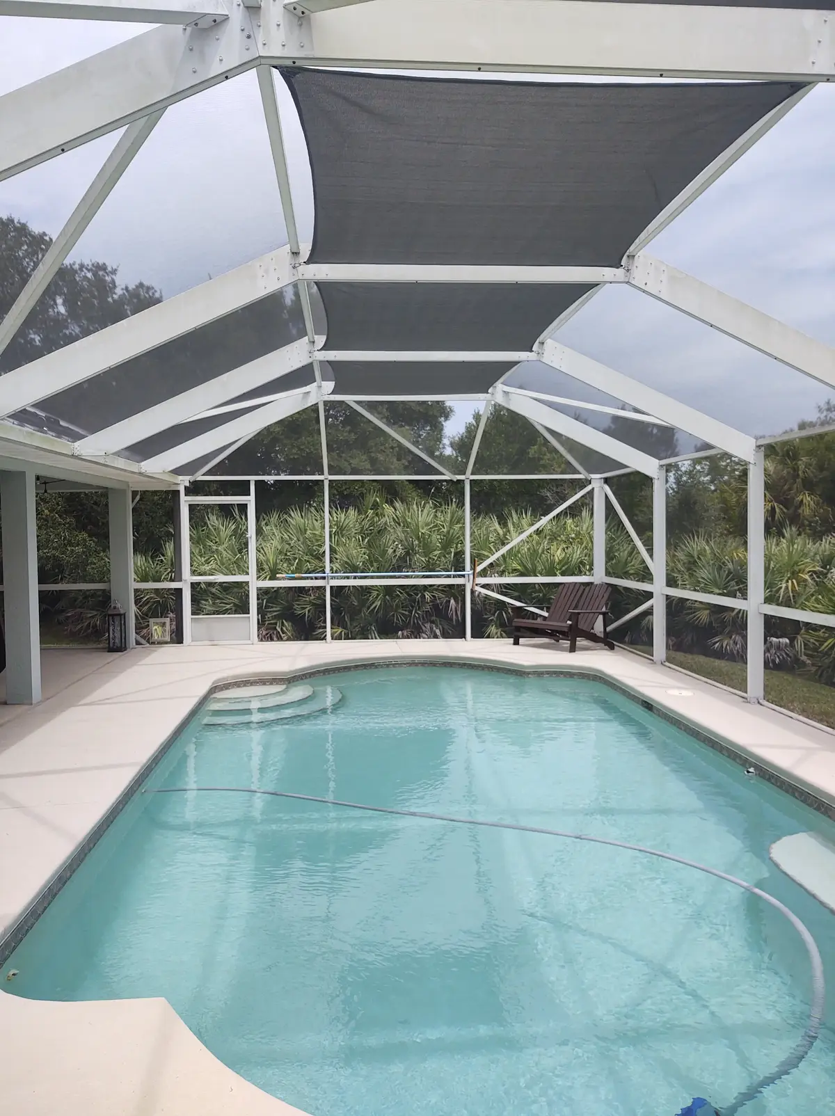 Tan SolaMesh shade sails providing UV defense in Fort Myers pool enclosure